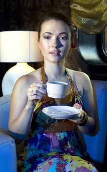 woman sitting on armchair and drinking tea in restaurant