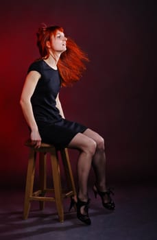 woman in black dress shake hair, red background