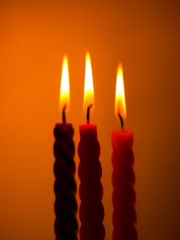 three twisted burning candles over yellow background