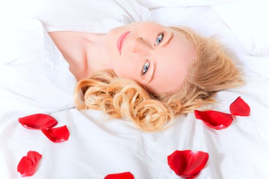 portrait of pretty woman laying in bed with rose petals