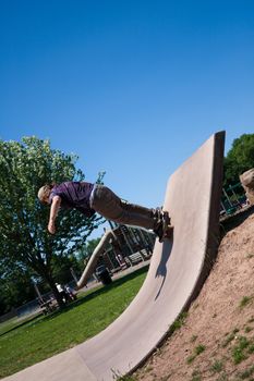 Action shot of a skateboarder going up a concrete skateboarding ramp at the skate park.