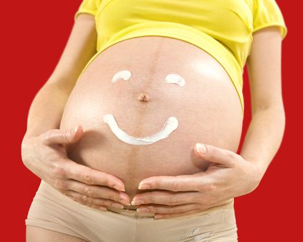 closeup body of pregnant woman on which smile is drawn