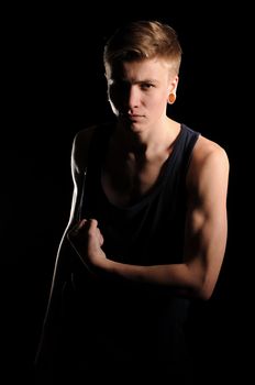 teenager showing muscles on the black background