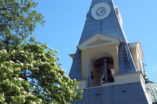 Bell tower with big clock on blue sky background