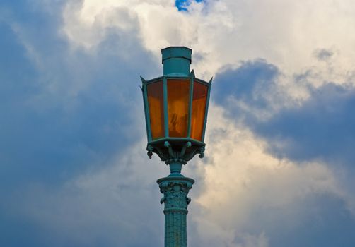 vintage street lamp with orange glass on cloud sky background