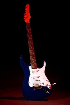 electric guitar in ray of red light on black background