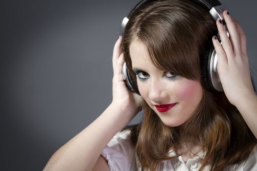 Beautiful Girl listening music over grey background