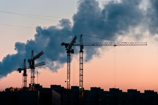 Cranes silhouettes with smoke on background at the morning with clear sky