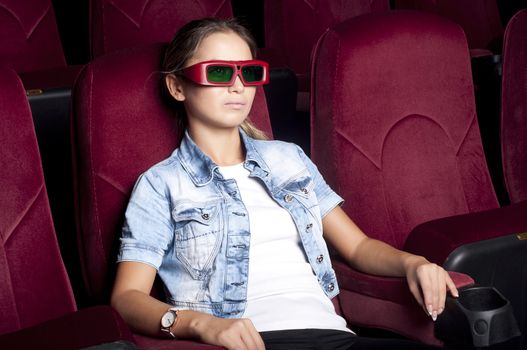 young woman sitting alone in the cinema and watching a movie