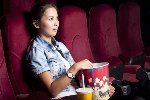 young woman sitting alone in the cinema and watching a movie