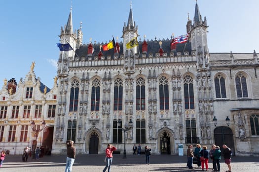 Tourists near a town hall in Bruges, Belgium, 29.09.1012. Bruges - the main town of the Belgian province the Western Flanders. One of the most picturesque cities of Europe.