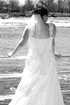 The back of a bride in her wedding dress over looking the water.