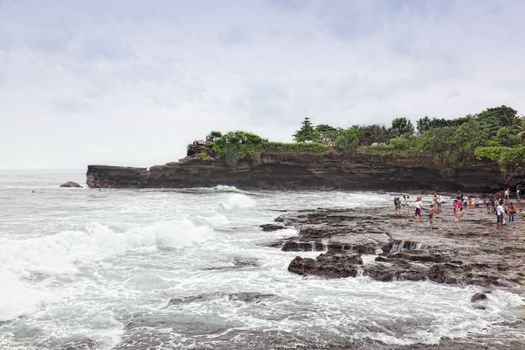 Tourists on an ocean coast near the temple Tana Lot, Bali, Indonesia 11.03.2012. Tanah Lot is one of the most important sea temples of Bali