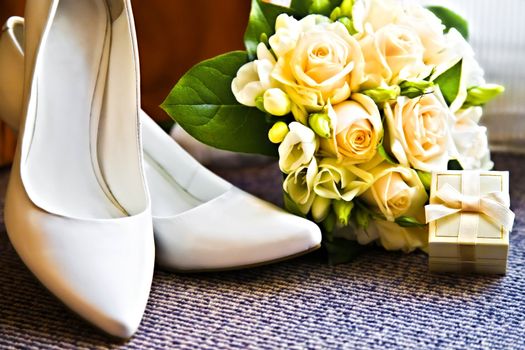 wedding rings in box with bouquet from roses and high heel shoes