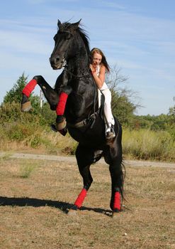 young woman and her rearing stallion outdoors