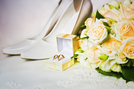 wedding rings in box with bouquet from roses and high heel shoes