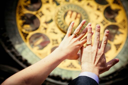 hands of newly married on clock background on the wall of Old Town City Hall in Prague, Czech Republic