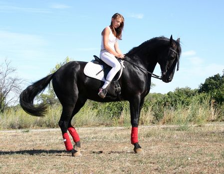 young woman and his black stallion in  a field