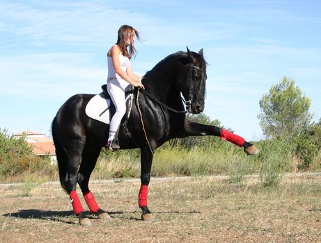 young woman and his black stallion in  a field