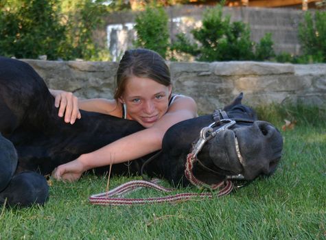 young riding girl and her black stallion laid down