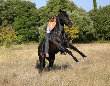 young woman and her rearing stallion outdoors