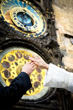 hands of newly married on clock background on the wall of Old Town City Hall in Prague, Czech Republic