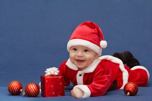 baby in santa's suit with gift and balls