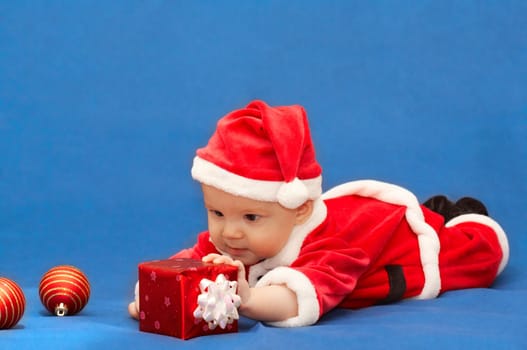 baby in santa's suit with gift and balls