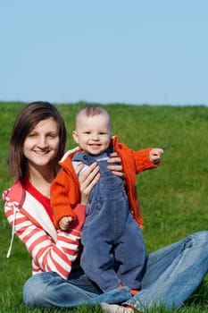 Happy mother with son sitting on green grass