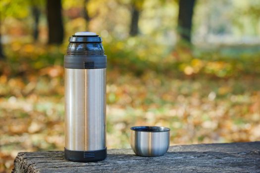 Thermos is on the bench in autumn park