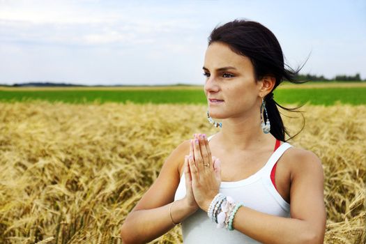 Beatiful and healthy natural young woman embracing nature by doing meditation, yoga or tai chi in a riped wheat field.