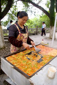 CHINA - MAY 9, A Chinese woman is selling fried tofu along the street in Guilin, China on 9 May, 2010.