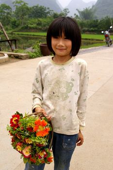 CHINA - MAY 16, A young girl is selling flowers for her family on Yangshuo, China on 16 May, 2010.