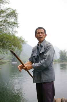 CHINA - MAY 16, A fisherman is paddling the bamboo boat along the Yulong River in Guilin, China on 15 May, 2010.