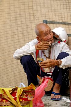 HONG KONG - AUG 1, An old man is sitting along the street and smoking in Hong Kong on 1 August, 2009.