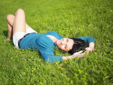 Young woman relaxing in park on green grass
