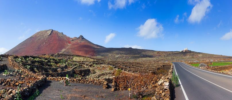 Empty road crossing the lava in the mountain, volcano backround. Panorama. Lanzarote, Canary islands, Spain