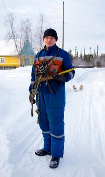 The worker-electrician in blue overalls  against the white snow