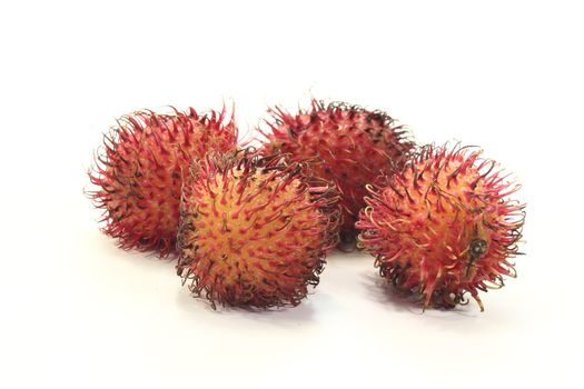 four fresh red rambutan before a light background