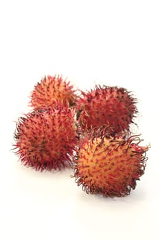 four red rambutan before a light background