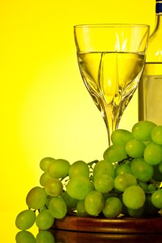 glass of white wine and grape, yellow background