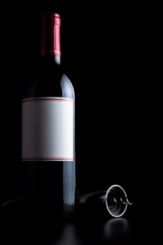 bottle of red wine and corkscrew isolated on black