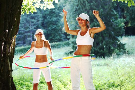 woman rotates hula hoop on nature background