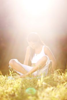 yoga woman on green grass lotus pose in sunrise light