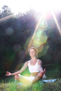 yoga woman on green grass lotus pose in sunrise light