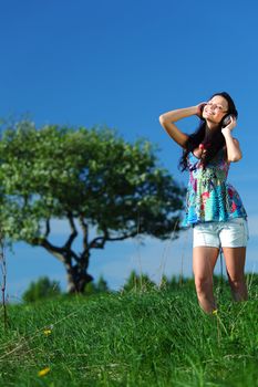 Young woman with headphones listening to music on field