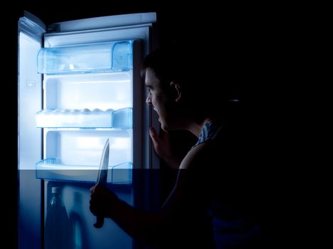 man with knife opening refrigerator door and sees something terrible