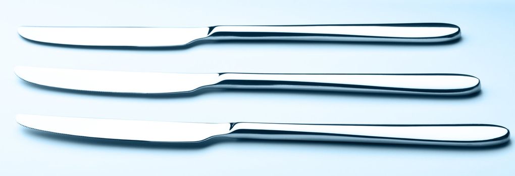 three table knives on blue background