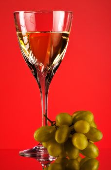 glass of white wine and grape, red background