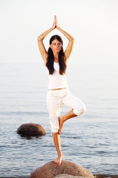 Young woman practicing yoga  near the ocean